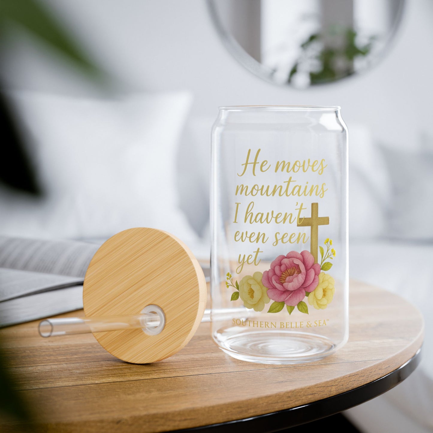 Clear glass drink container with floral design and text on a wooden table.