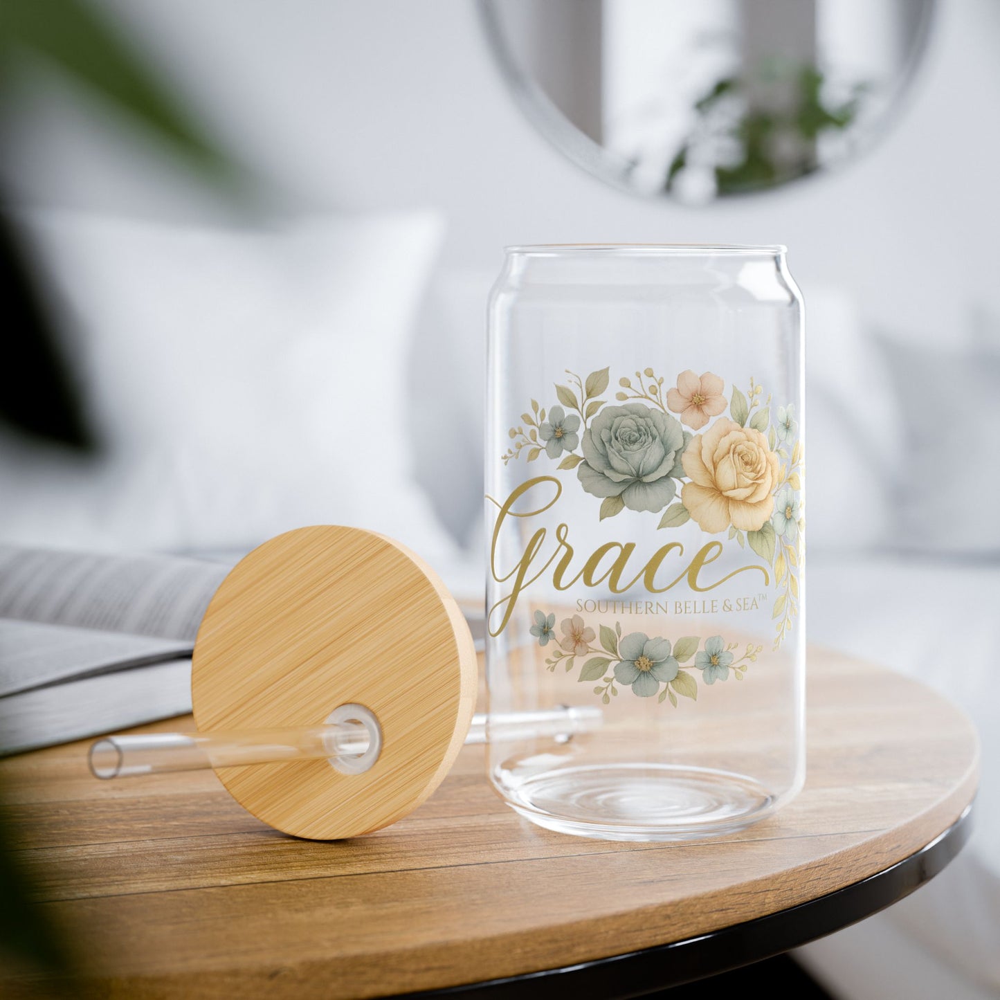 Clear glass tumbler with floral design and 'Grace' text on a wooden table.