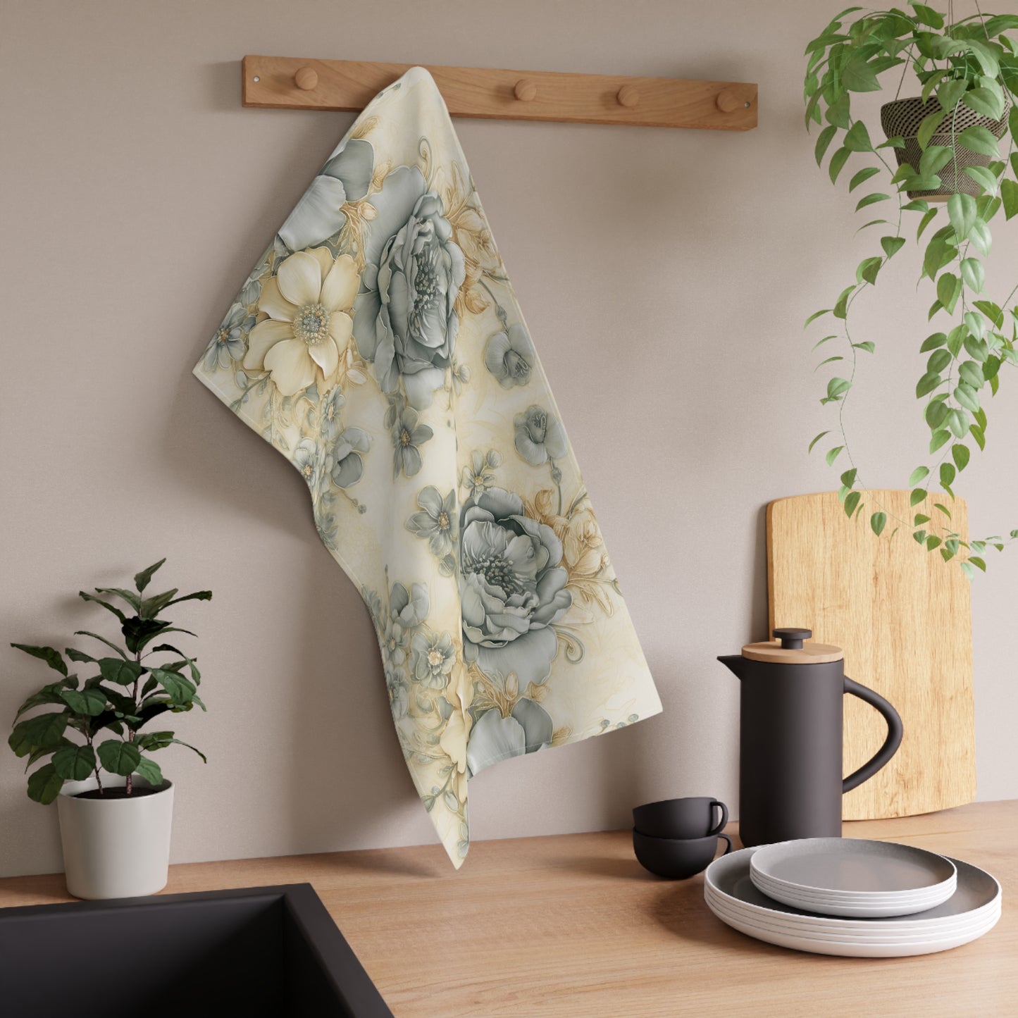 Floral towel hanging on a wooden rack with kitchen items and plants in the background