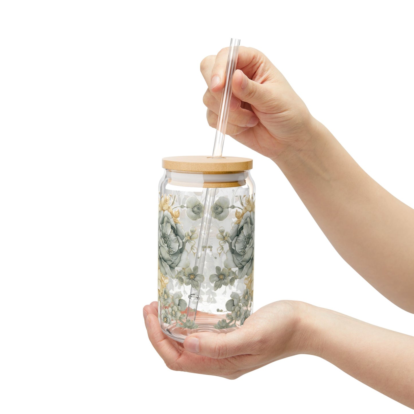 Glass jar with a wooden lid and straw held by a hand on a white background