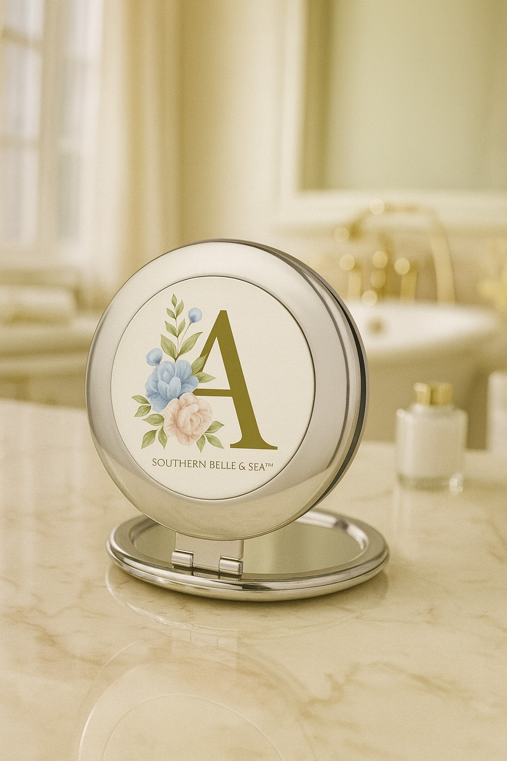 Compact mirror with floral design and 'A' on a bathroom counter
