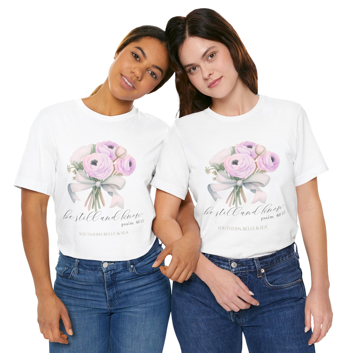 Two women wearing white t-shirts with floral designs and text, standing close together on a white background.