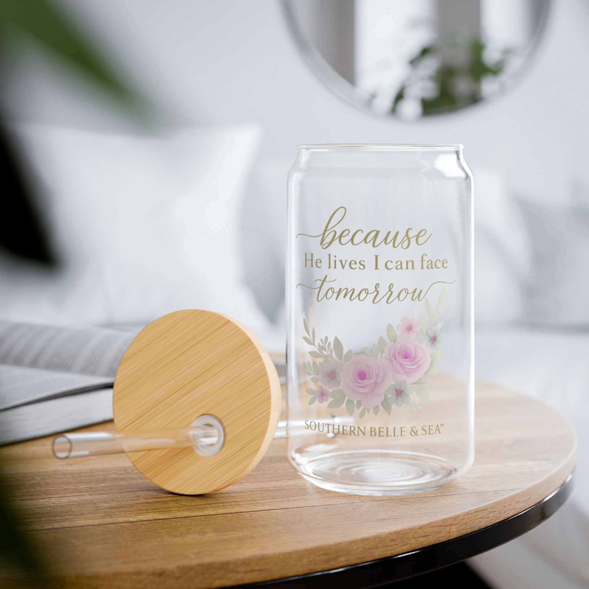 Glass drink container with floral design and text on a wooden table