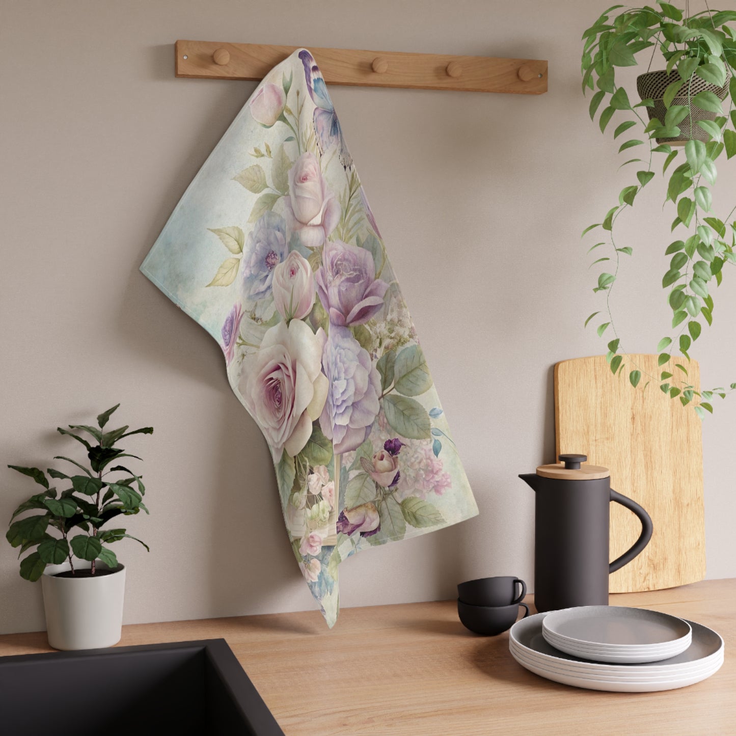 Floral towel hanging on a wooden rack with kitchen items and plants in the background