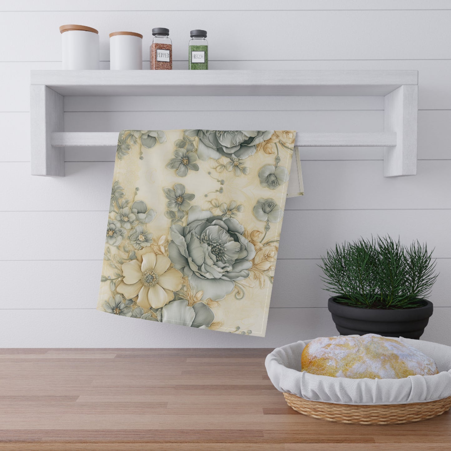 Floral towel hanging on a white shelf with a plant and basket in the foreground.