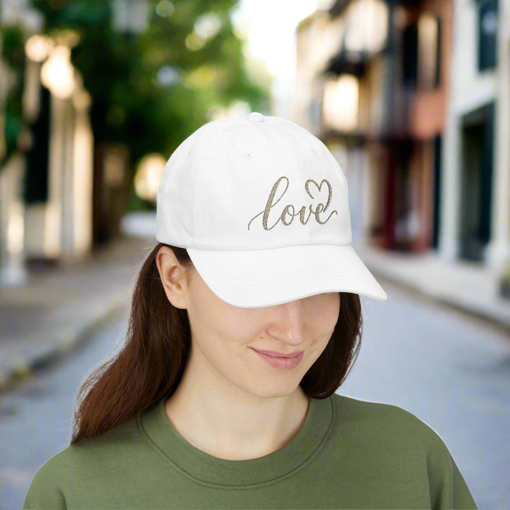 White cap with 'love' and heart design worn by a person on a white background