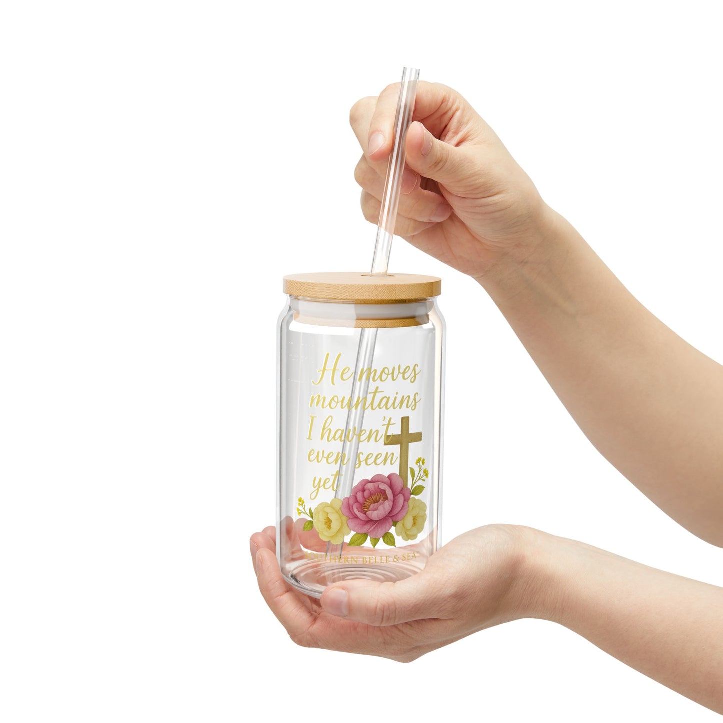 Glass tumbler with wooden lid and floral design held by a hand on a white background
