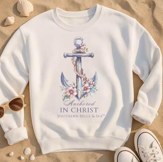 White ANCHORED IN CHRIST CHRISTIAN BEACHWARE sweatshirt with anchor design and text on a sandy background