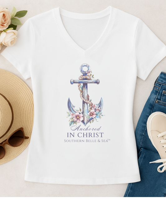 White t-shirt with anchor design and text 'Anchored In Christ' on a neutral background with accessories.