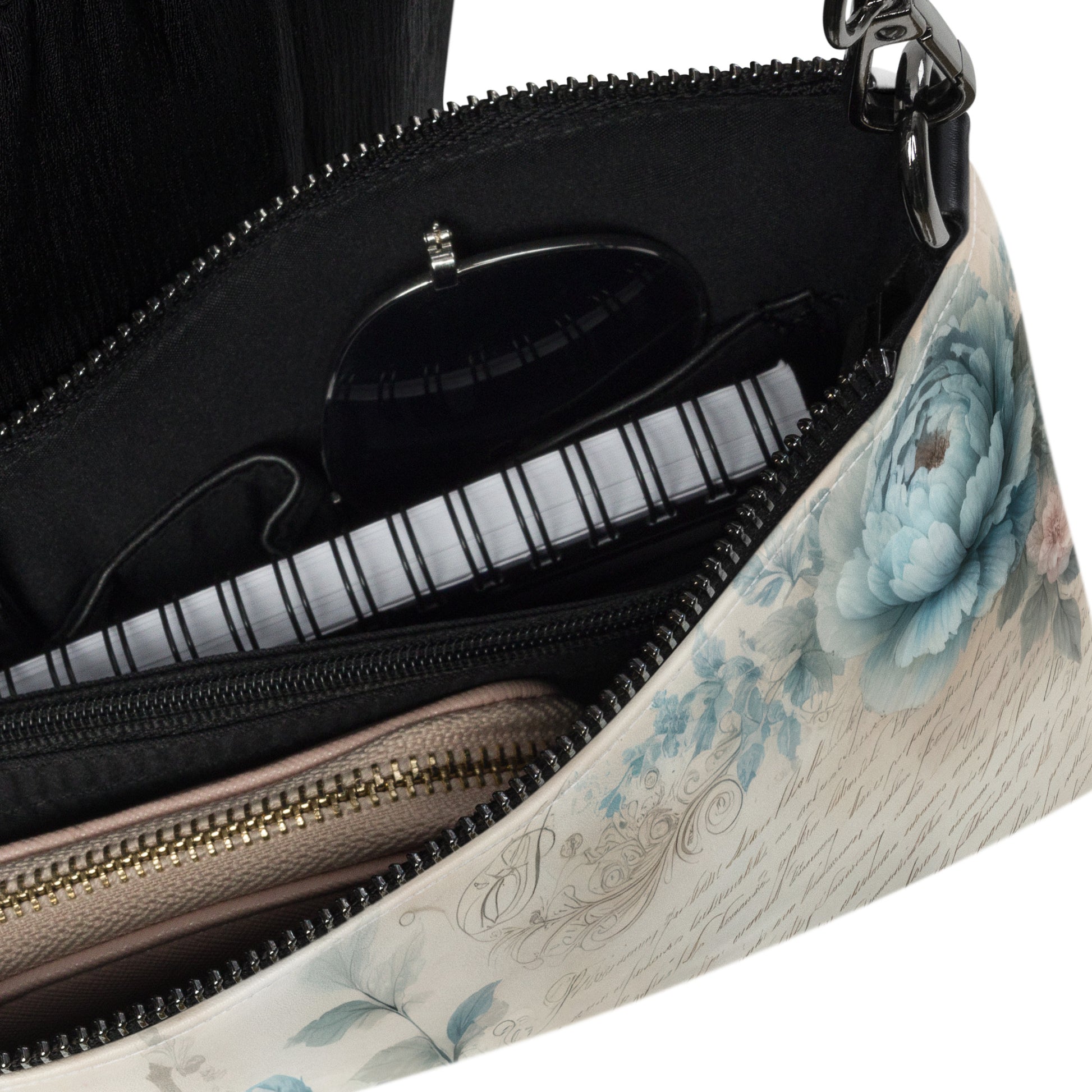 Interior view of crossbody bag showing spacious pockets with zipper, sunglasses, and notebook
