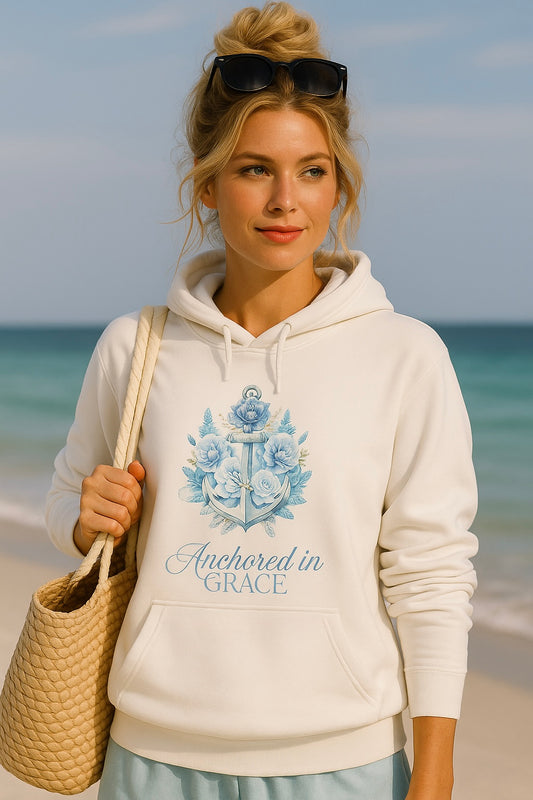 Anchored in Grace Unisex Hoodie | Southern Belle & Sea™ — woman wearing white hoodie with blue anchor floral design, styled with woven tote on the beach.
