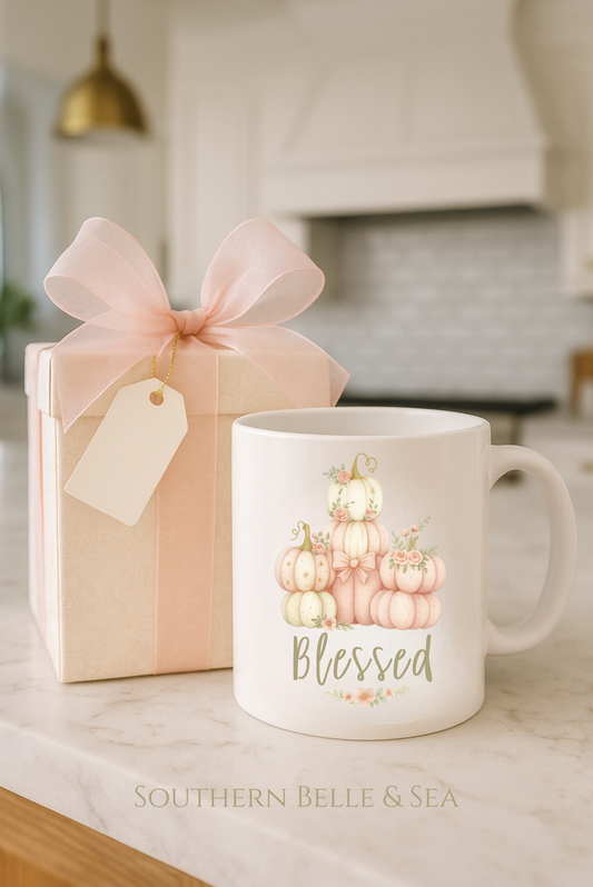 Mug with pumpkin design and 'Blessed' text next to a gift box on a kitchen counter.