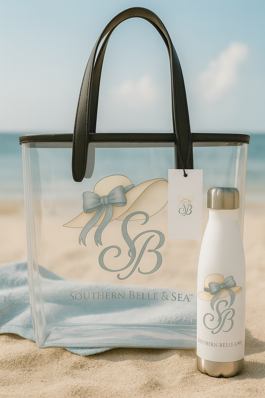 Southern Belle & Sea™ clear tote and bottle set with monogrammed blue bow and sunhat, styled on the sand by the ocean for a chic beach look.

